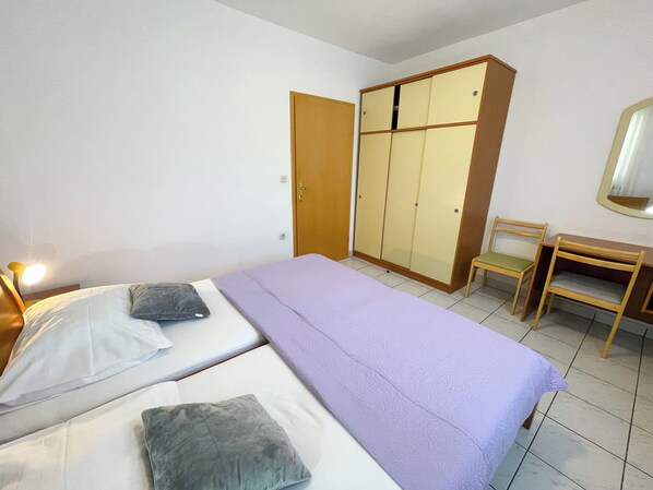 Une chambre avec deux lits, une armoire, un bureau et une chaise.