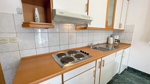 Una cocina con estufa, lavaplatos y armarios.