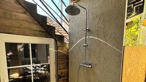 A wooden deck with a shower area, a door with windows, and a view of the outside. - Apart 50m² 5 People 2 Bedrooms –Town, Train, Beach few mn (La Bernerie-en-Retz)
