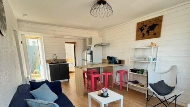 A compact living space with a blue sofa, a white coffee table, and a dining area with red chairs. - Lovely Apart. 55m² - 5 People / 2 Bedrooms, Terrace sea view (La Bernerie-en-Retz)