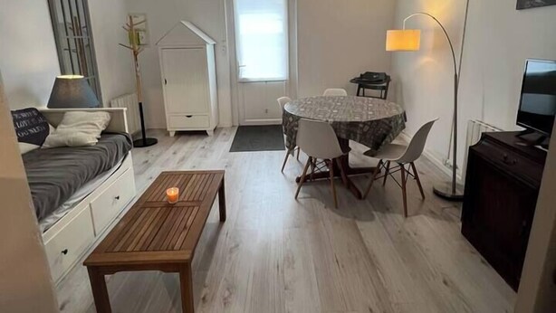Ein gemütlicher Wohnbereich mit Bett, Esstisch mit Stühlen, Couchtisch, Fernseher und Lampe.
