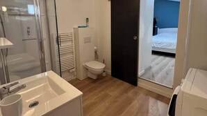 Ein modernes Badezimmer mit Duschkabine aus Glas, einem weißen Waschbecken und einer Toilette.
