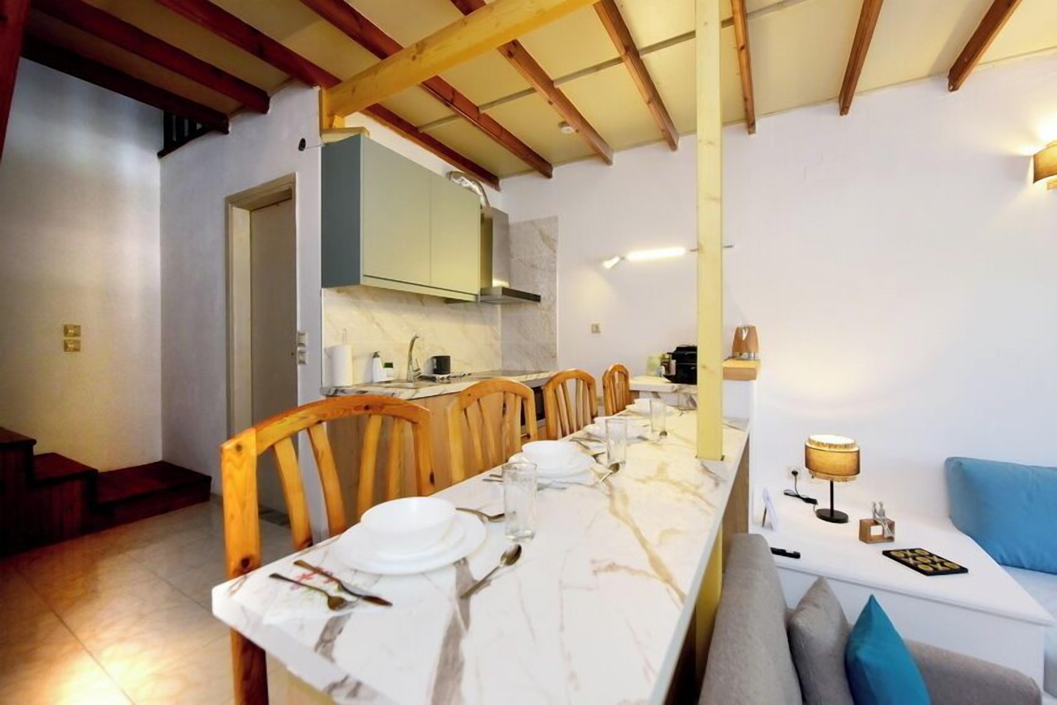 A dining area with a marble table, wooden chairs, and a sofa with cushions.
