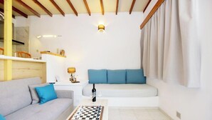 A modern living room with a sofa, a coffee table with a chessboard, a lamp, and a wall-mounted light fixture.