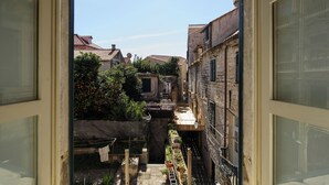 A narrow alleyway with buildings on either side, a small bridge, and a view of the sky.