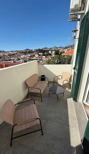 Un balcon agrémenté de meubles en osier, d’une petite table et offrant une vue sur la ville.
