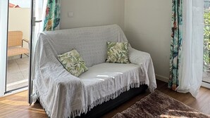 A room with a sofa, a rug, and a painting on the wall.