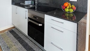 A modern kitchen with white cabinets, a black countertop, and a stainless steel oven.