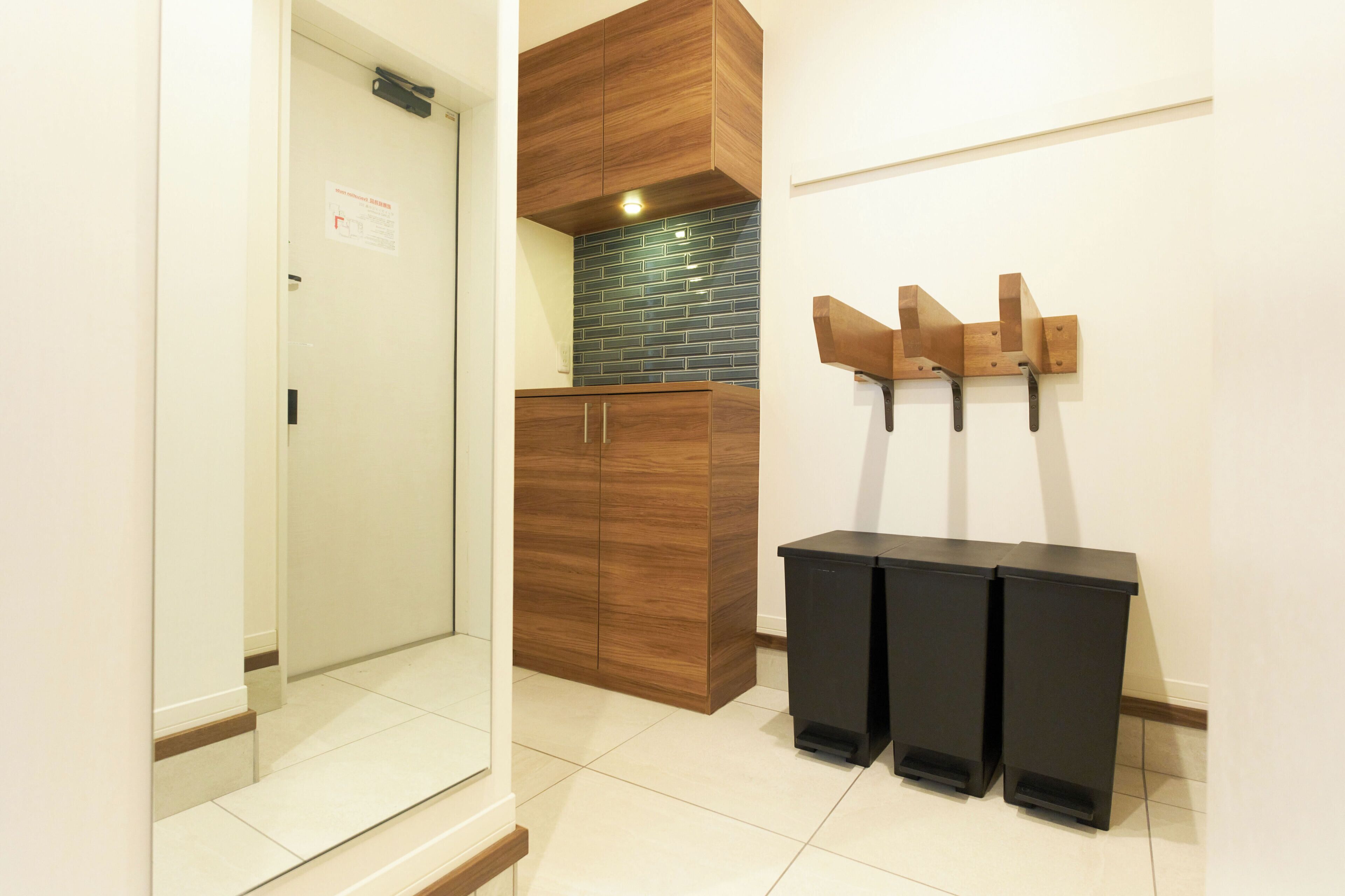 A hallway with a wooden wardrobe, a tiled backsplash, and a wall-mounted coat rack.
