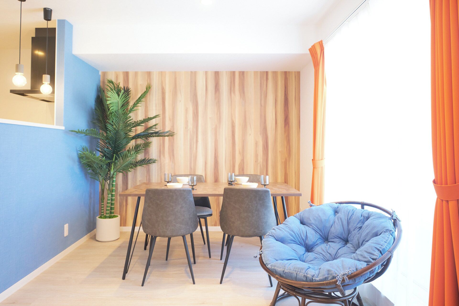 Een eethoek met een houten wand, twee grijze stoelen, een tafel met een wit tafelkleed en een potplant.