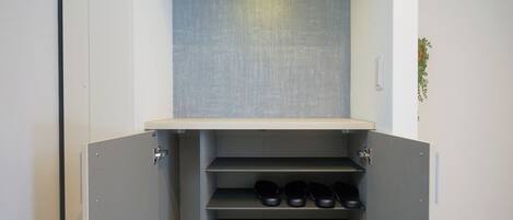 A built-in shoe storage unit with multiple shelves and a light fixture above.