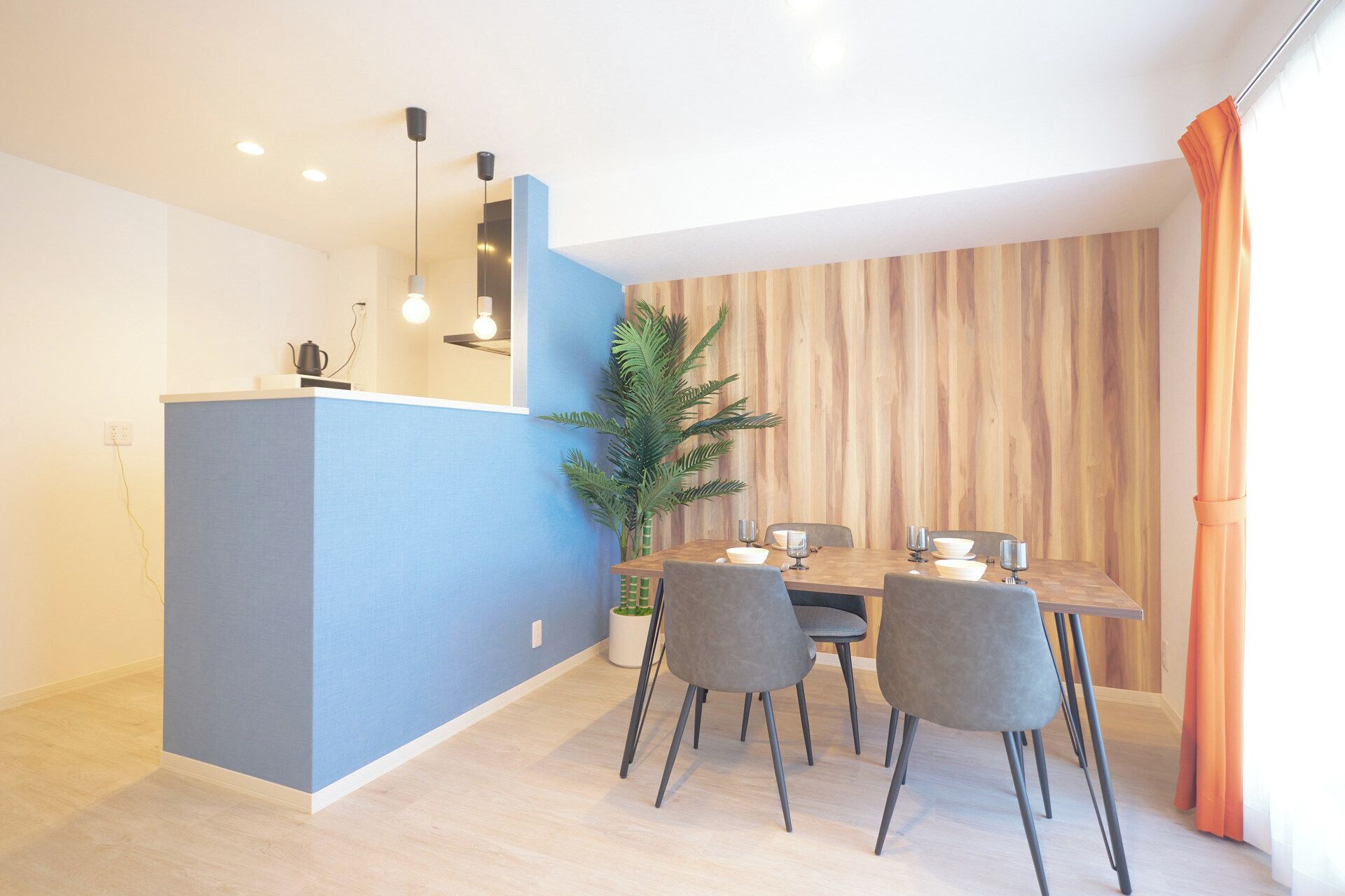 Un comedor moderno con una pared azul de acento, un revestimiento de madera y una mesa de comedor con sillas.
