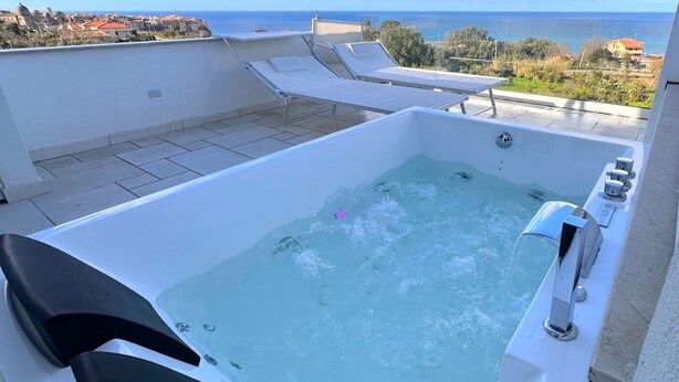 A rooftop jacuzzi with a view of the sea, lounge chairs, and a clear sky. - Aurantia - Mediterranean Tale (Tropea)