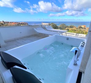 A rooftop jacuzzi with a view of the sea, lounge chairs, and a clear sky. - Aurantia - Mediterranean Tale (Tropea)