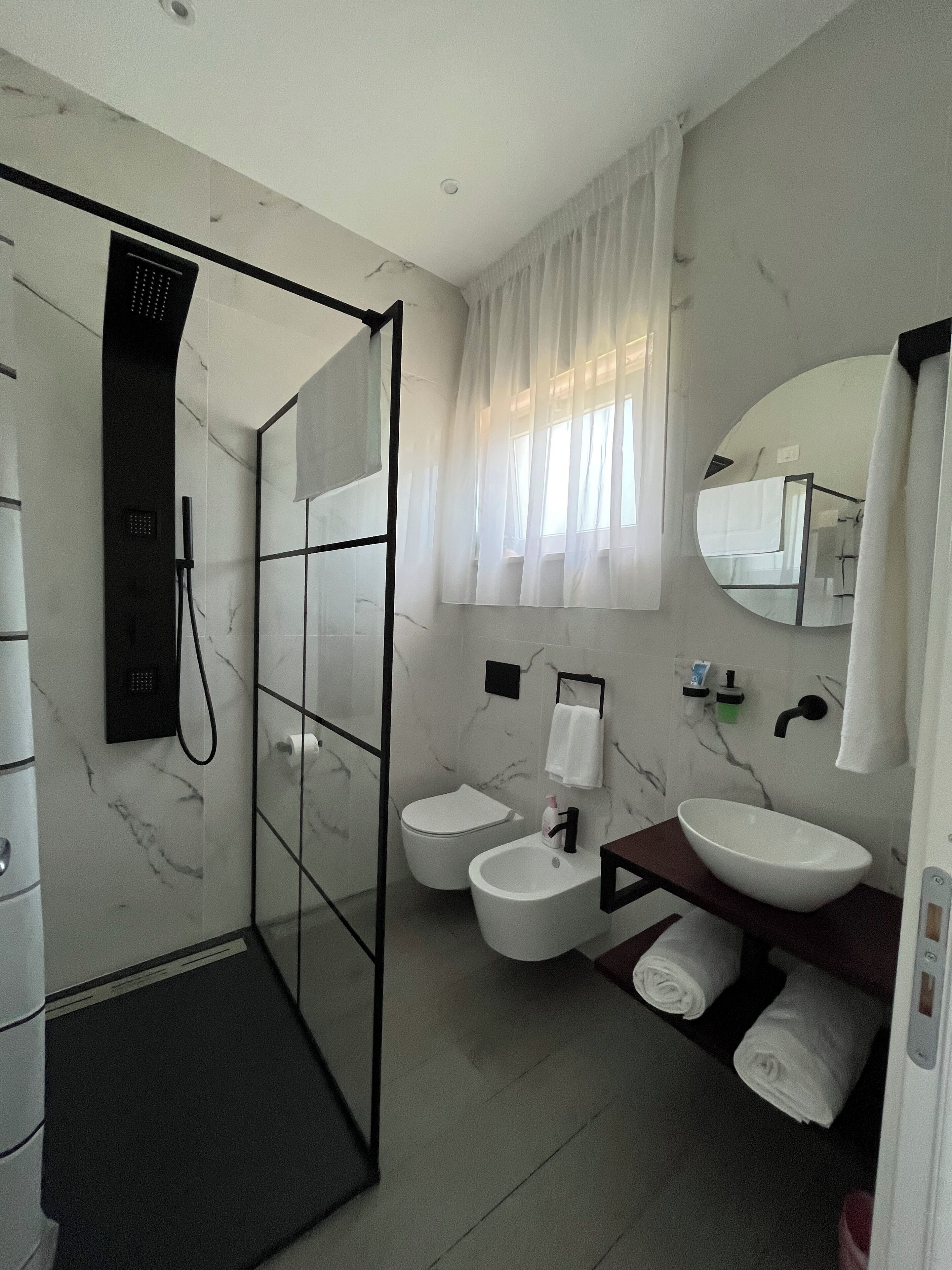 A modern bathroom with a glass shower enclosure, a toilet, a bidet, and a sink.