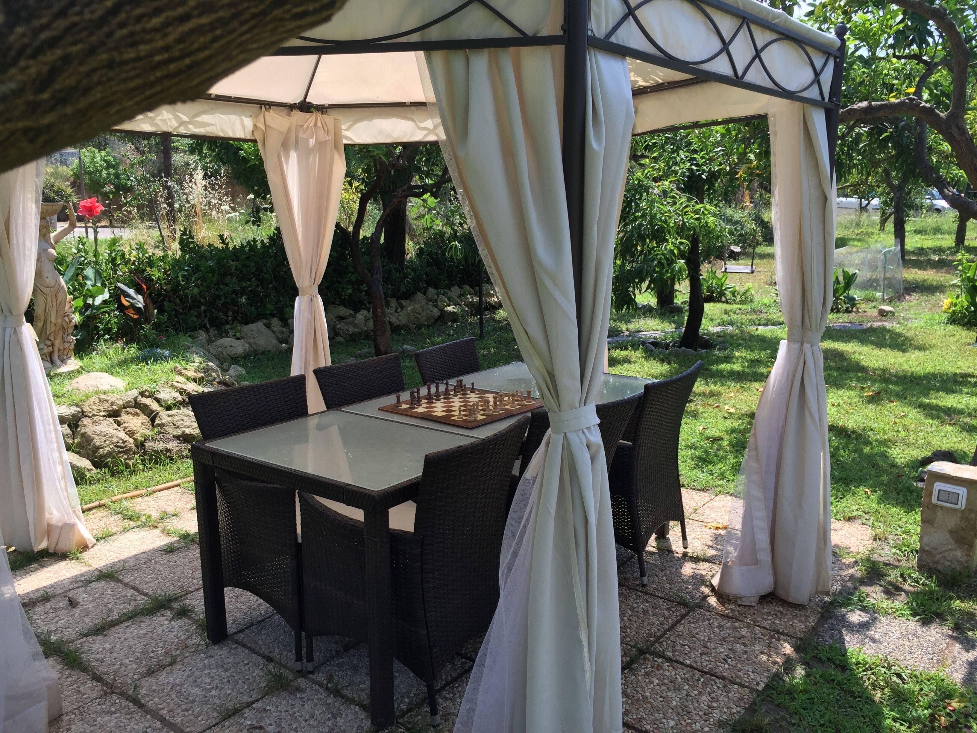 Un patio al aire libre con una mesa de ajedrez y sillas bajo una marquesina.