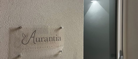 A textured wall with the name "Aurantia" and a frosted glass door with a handle.