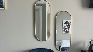 A room with a blue upholstered chair, a gold-framed mirror, and a smaller mirror with a leaf design. - Aurantia - Mediterranean Tale (Tropea)
