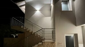 A modern building with a staircase leading to a second floor, a door with a glass panel, and a small window on the upper floor. - Aurantia - Mediterranean Tale (Tropea)