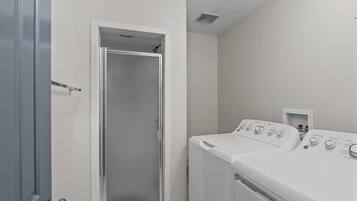A laundry room with a door leading to a shower, and two front-loading washing machines.