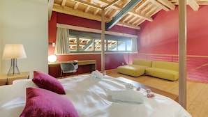 A bedroom with a bed, a desk, a chair, a sofa, and a window. - Almavite Wine Resort (Desenzano del Garda)