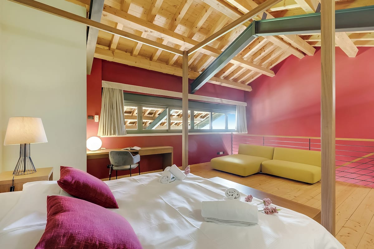 Un dormitorio con cama, escritorio, silla, sofá y ventana.