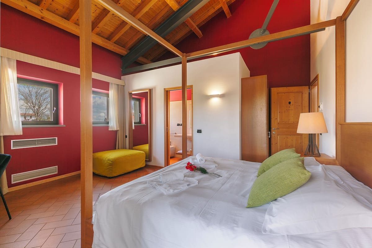 Una habitación con una cama con dosel, un banco amarillo y techo de madera.