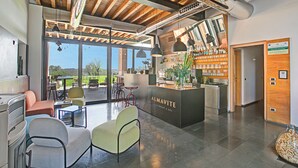 A modern interior with a reception desk, seating area, and a view of the outdoors. - Almavite Wine Resort (Desenzano del Garda)