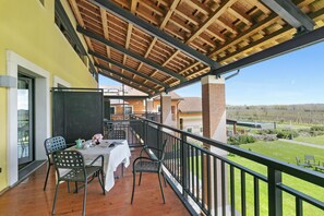 Enjoy a serene vineyard view from this balcony with a table for al fresco dining.