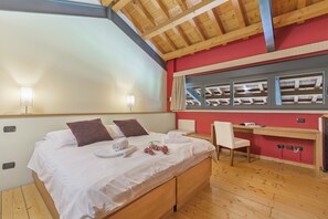 Cozy retreat with a large bed, desk, and floral arrangement, offering a peaceful workspace and scenic views.