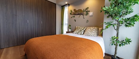 Un dormitorio con una cama grande, un armario, un adorno de estampado de leopardo en la pared y una planta en maceta.