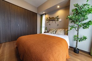 A bedroom with a large bed, a wardrobe, a wall-mounted leopard print decoration, and a potted plant. - Cure Azumabashi by Tranova (Tokyo)