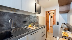 A modern kitchen with a marble countertop, stainless steel sink, and a built-in oven. - Montagne E Coccole (Pre-Saint-Didier)