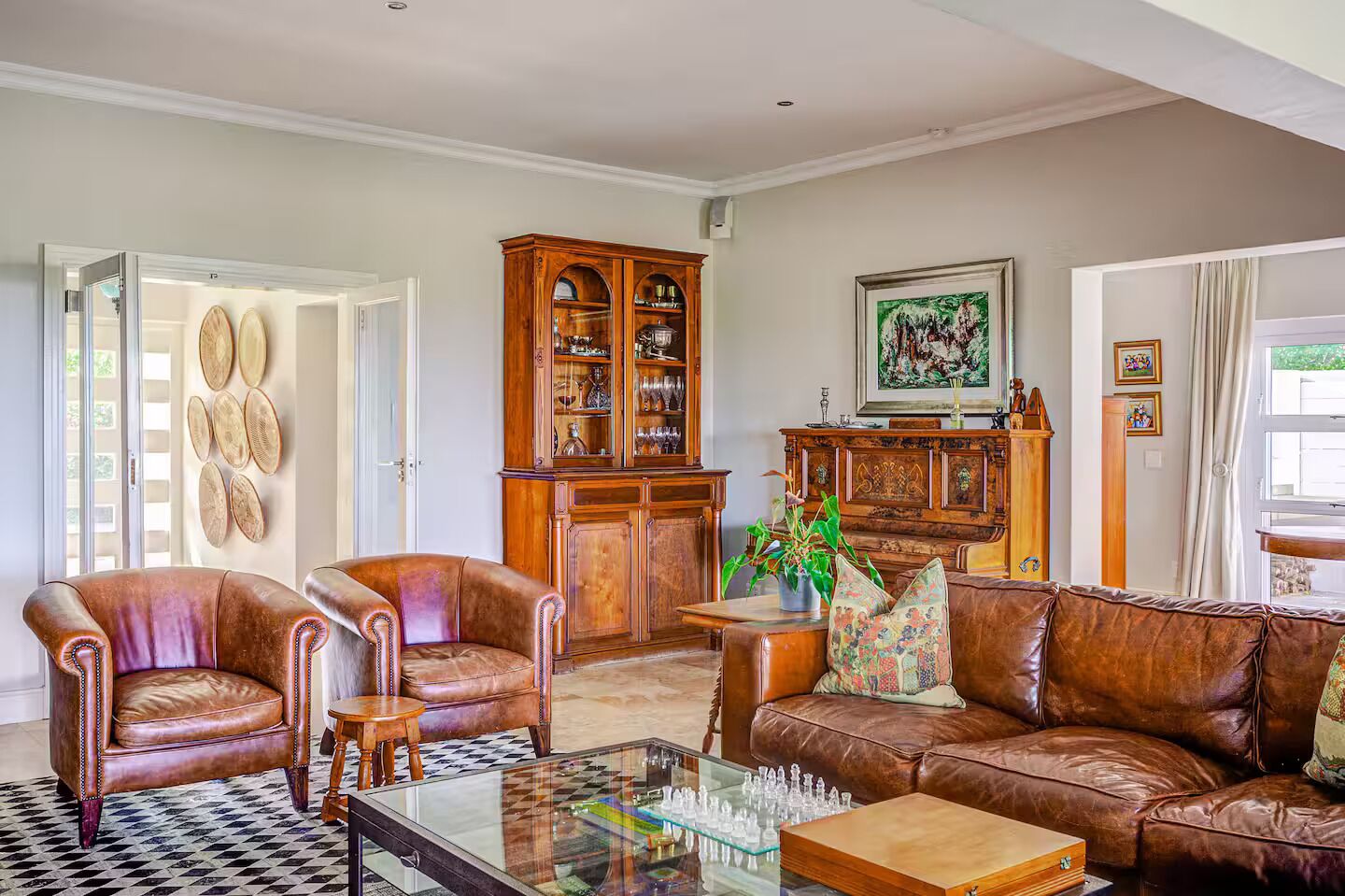 A living room with leather sofas, a glass coffee table, and a wooden cabinet with glass doors.