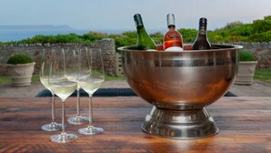 A metal bowl on a wooden table with three wine glasses and two bottles of wine. - 4-bedroom house overlooking the sea on the cliff path in Hermanus (Hermanus)