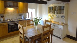 A kitchen with wooden cabinets, a stove, and a dining table with chairs.