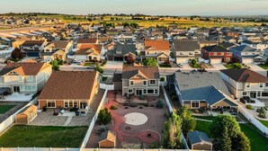 Un quartier résidentiel avec des maisons, un terrain de basket et, au fond, un espace vert.