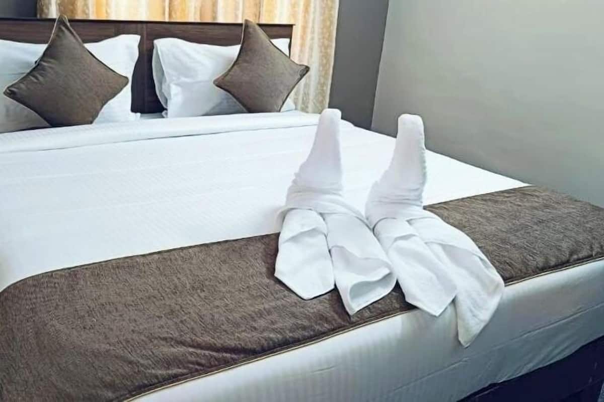Un lit bien fait, avec du linge de lit blanc, des oreillers marron et un motif marron sur la couvre-lit.
