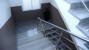 Eine Treppe mit Metallgeländern, einem Blumentopf und einem Fenster.