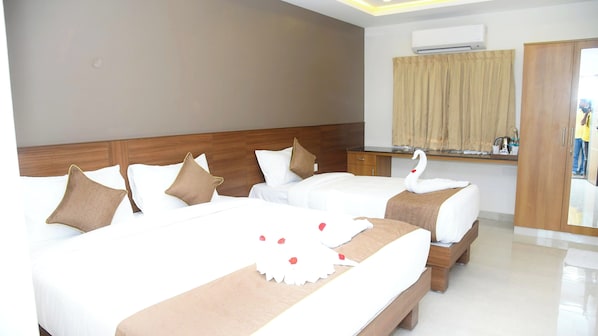 Habitación de hotel con dos camas, cabecero de madera, ventana con cortinas, unidad de aire acondicionado y una zona de kitchenette.