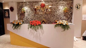 A reception desk with 'PVR RESIDENCY' signage, floral decorations, and a marble wall background.