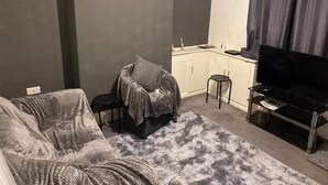 A compact living space with a sofa, a small chair, a television, and a kitchenette area. - 2br-sleeps3 -family Friendly -free Parking -garden (Nottingham)