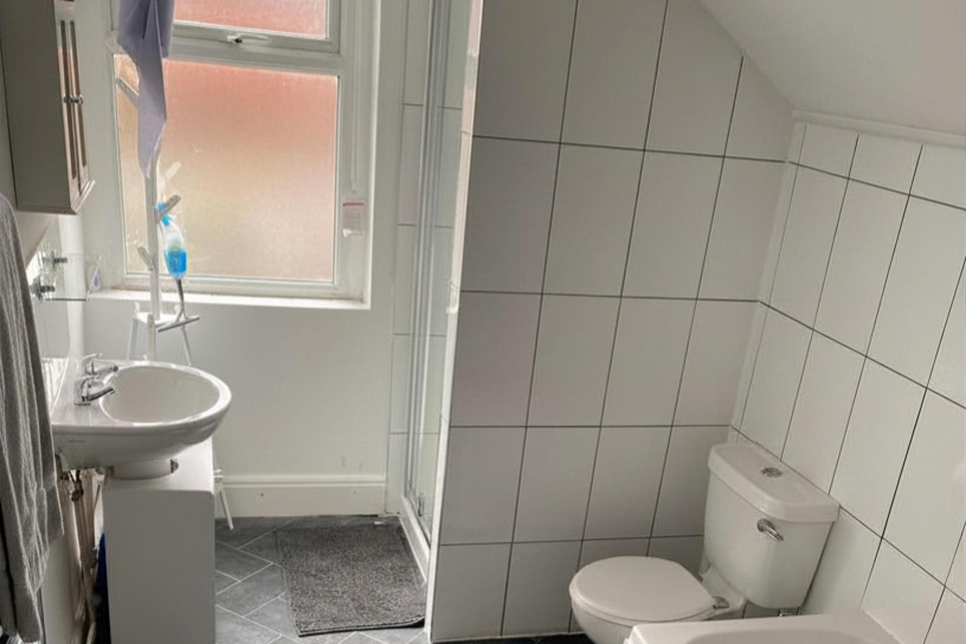 A small bathroom with a sink, toilet, and window.