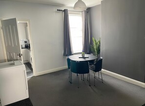 A compact room with a round table, two chairs, a potted plant, and a window with curtains. - 2br-sleeps3 -family Friendly -free Parking -garden (Nottingham)