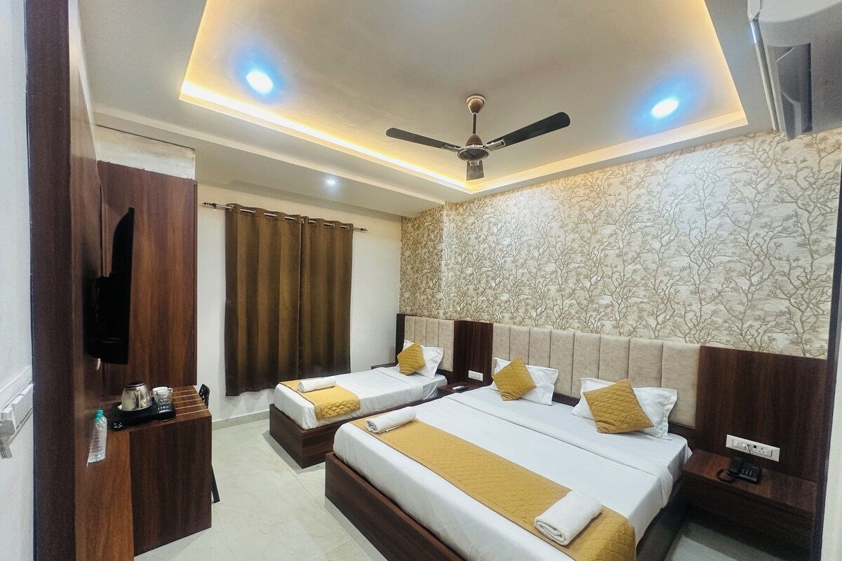 A hotel room with two beds, a ceiling fan, and a small desk with a telephone.