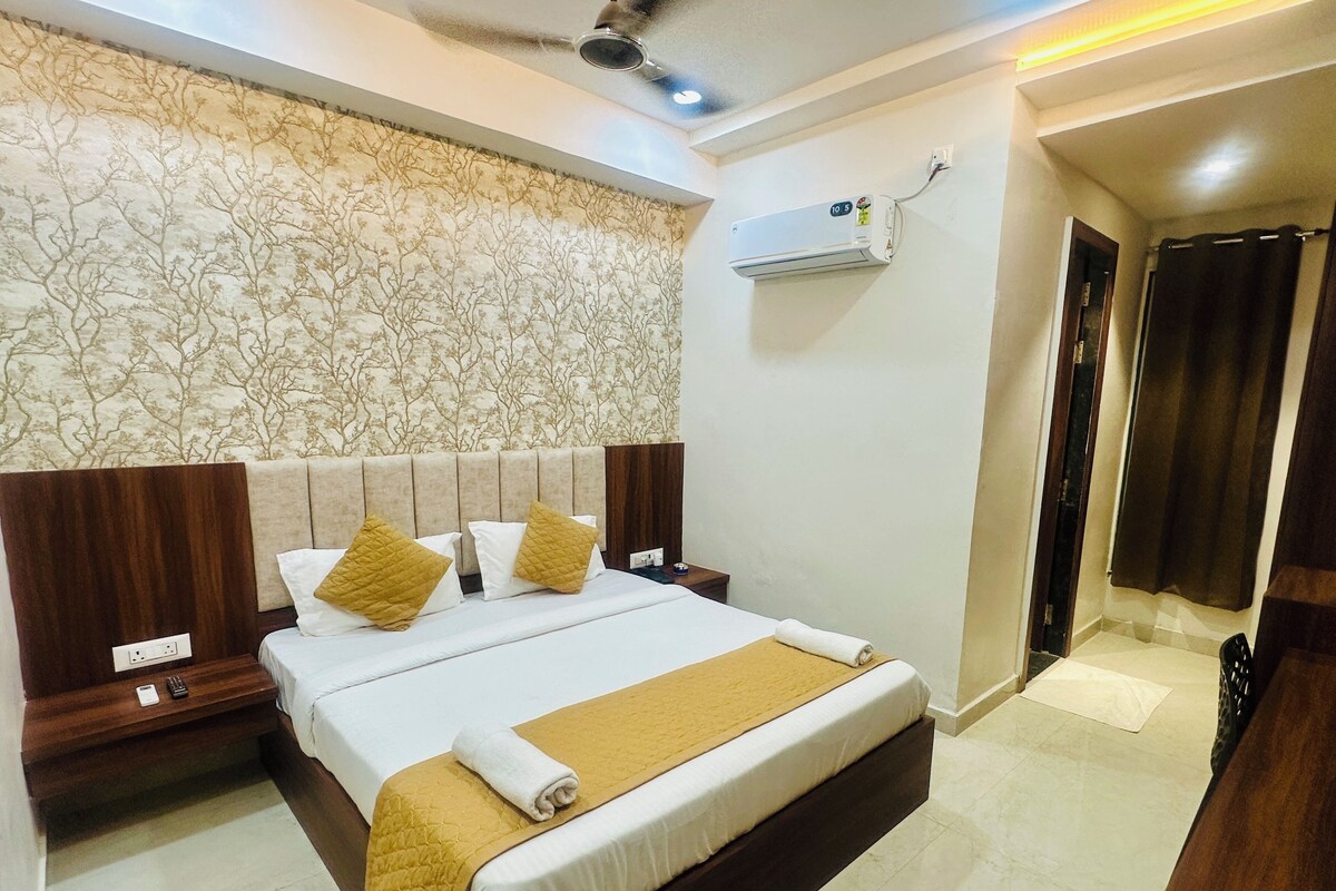 A neatly made bed with a headboard, a bedside table with a lamp, and an air conditioning unit on the wall.