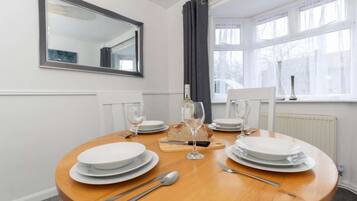 A dining table set for four with plates, cutlery, and wine glasses.