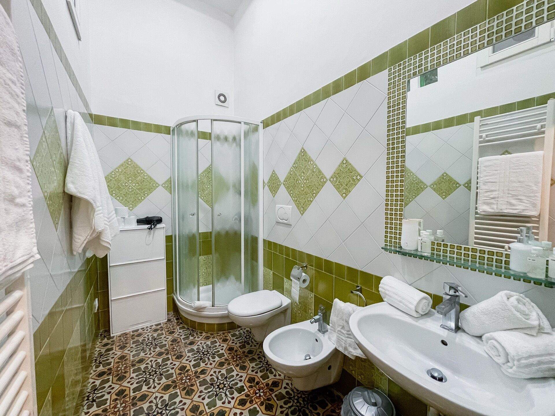Een badkamer met een douche, twee toiletten, een bidet en een wastafel.
