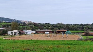 A fenced equestrian arena with jumps and a covered seating area. - La Casa di Amalia in Ponte (Budoni)