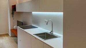 A modern kitchen with white cabinetry, a stainless steel sink, and a built-in oven. - 4bnb - Charming Giuliana Apartment (Rome)